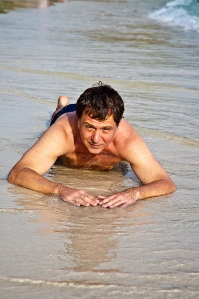 Uomo sdraiato sulla spiaggia — Foto Stock