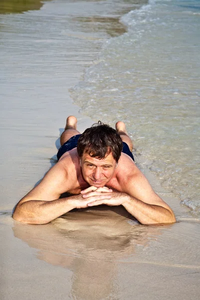 男子躺在沙滩上 — 图库照片