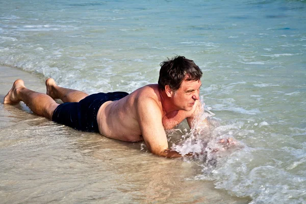 Człowiek leżący na plaży — Zdjęcie stockowe