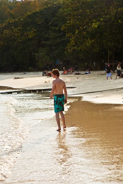 Маленький мальчик идет по красивому пляжу в подсветке — стоковое фото