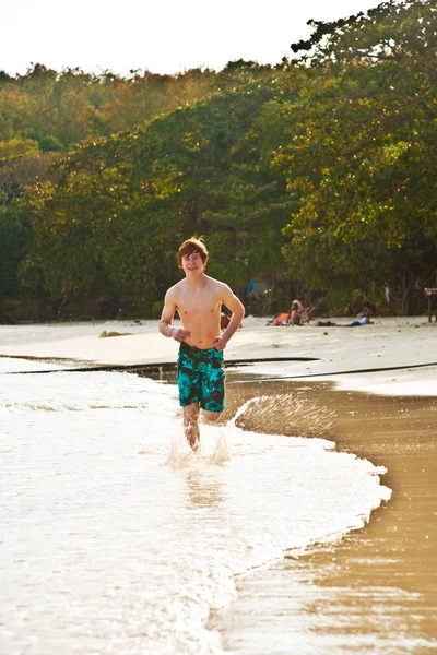 Jeune garçon se promène le long de la belle plage en contre-jour — Photo