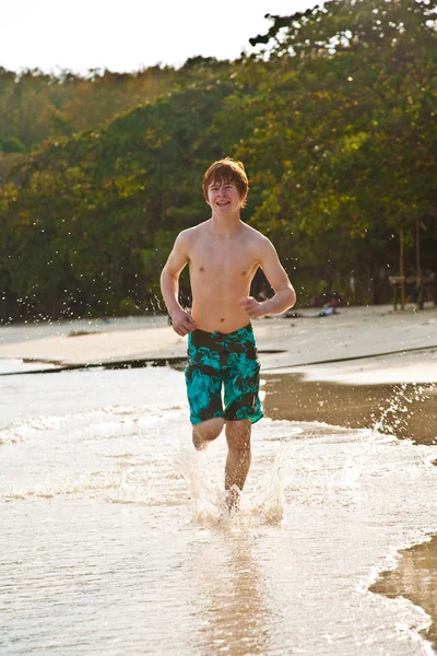 Niño está caminando a lo largo de la hermosa playa en la luz de fondo — Foto de Stock