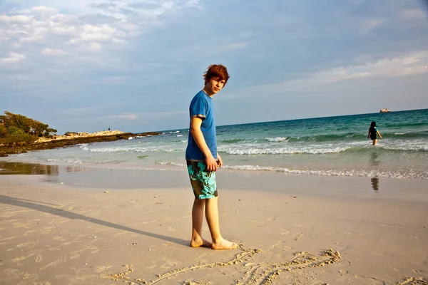 Niño con el pelo rojo está disfrutando de la hermosa playa y la pintura en sa —  Fotos de Stock