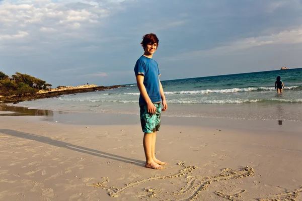 Menino com cabelo vermelho está desfrutando da bela praia e pintura em sa — Fotografia de Stock