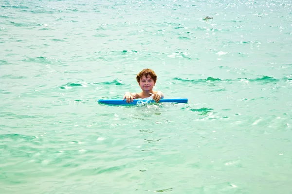 Joven chico disfruta de montar en la tabla de surf en el hermoso mar — Foto de Stock