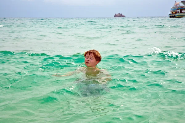 Ung pojke har ridning på surfbräda i det vackra havet — Stockfoto
