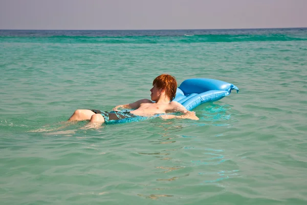Kinderen zijn zwemmen en met behulp van een lucht-matras om te ontspannen aan de duidelijke se — Stockfoto