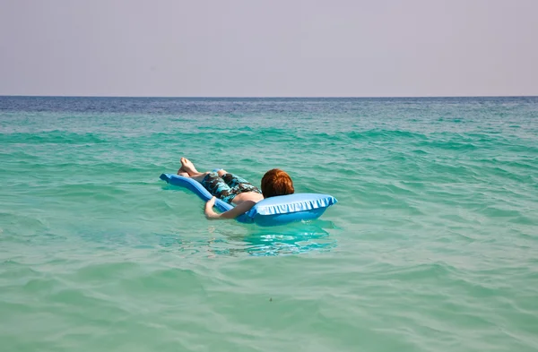 Barn är simning och använder en luft-madrass för avkoppling på den tydligt se — Stockfoto