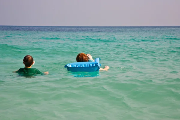 Barn är simning och använder en luft-madrass för avkoppling på den tydligt se — Stockfoto