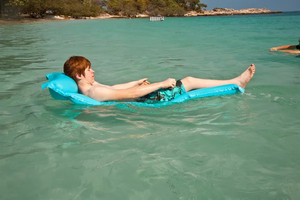 Menino usa o colchão de ar para relaxar no mar claro — Fotografia de Stock