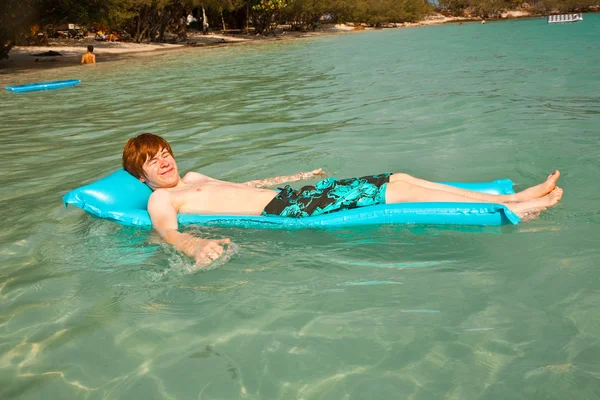 少年澄んだ海でリラックスのための空気マットレスの使用します。 — ストック写真
