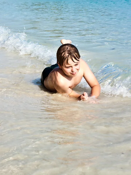 Pojken har kul i underbara varma havet och har vattnet — Stockfoto