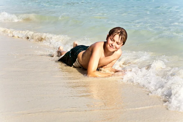 Αγόρι έχει διασκέδαση στον ωκεανό θαυμάσια ζεστό και απολαμβάνει το νερό — Φωτογραφία Αρχείου