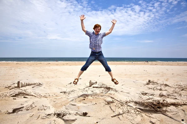 Pojken har den vackra stranden och hoppar — Stockfoto