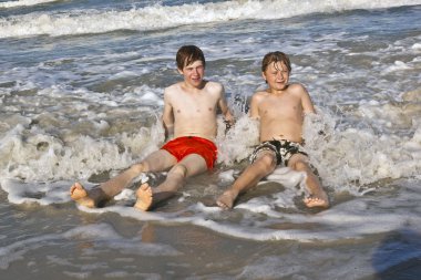 Brothers have fun at the beautiful neach of the ocean clipart