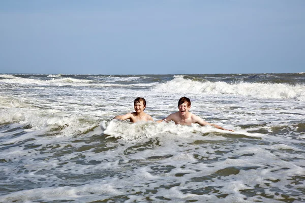 Meninos desfrutando as ondas no oceano selvagem — Fotografia de Stock