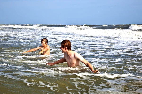 Мальчики наслаждаются волнами в диком океане — стоковое фото