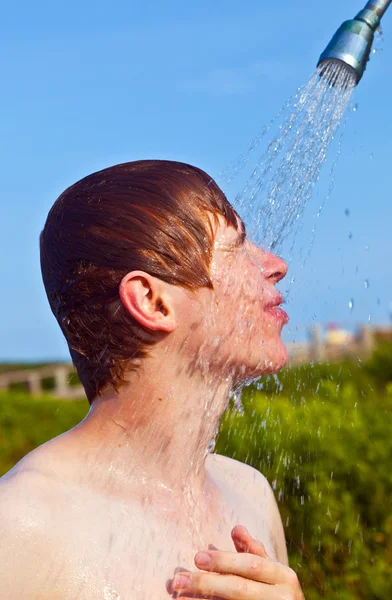 Jongen heeft een douche op het strand — Stockfoto
