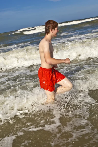 浜の水を通って走っている少年 — ストック写真