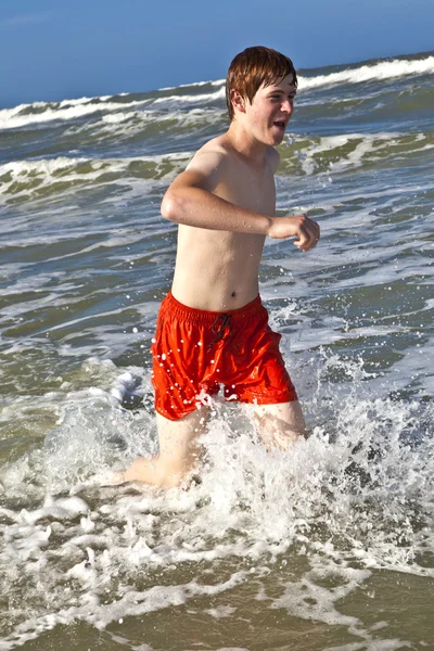 Pojke kör genom vattnet på stranden — Stockfoto