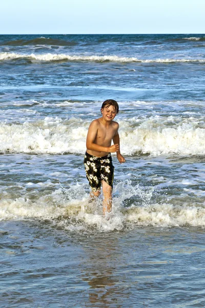 Fiatal fiú, fut át a víz, a strandon — Stock Fotó