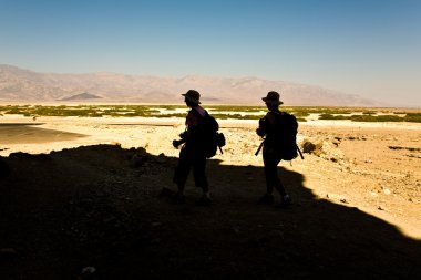 Two trackers come back from a track in Death valley to the parking place clipart