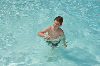 Young boy has fun in the pool clipart