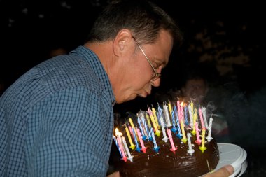 Man blows out his birthday candles clipart