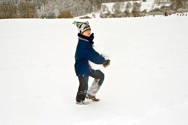 Kind hat einen großen Schneeball für den Schneemann in der Hand — Stockfoto