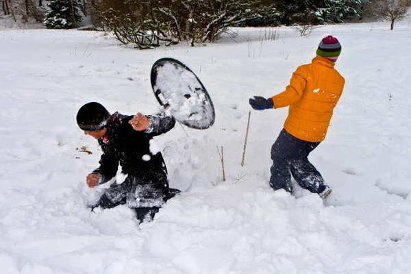 Los niños tienen una pelea de bolas de nieve en el área de nieve — Foto de Stock