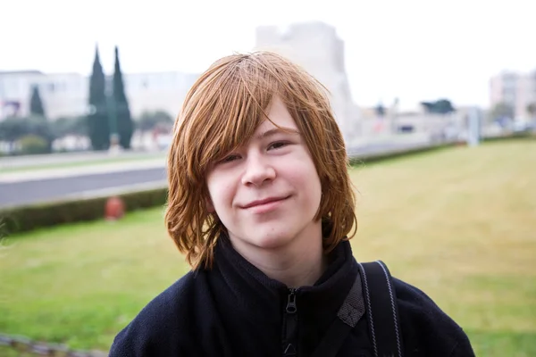 Menino com cabelo vermelho está sorrindo e olhando feliz — Fotografia de Stock