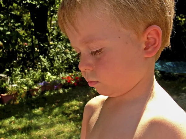 stock image Cute young boy in the garden looking sad