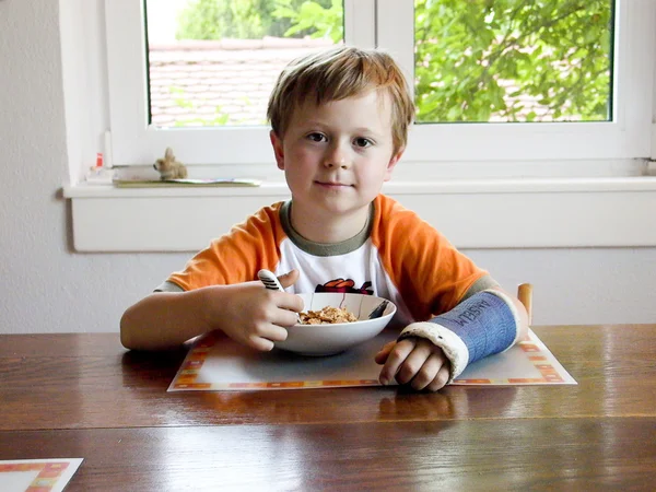 Chlapec na snídani s obsazení na zlomenou ruku — Stock fotografie