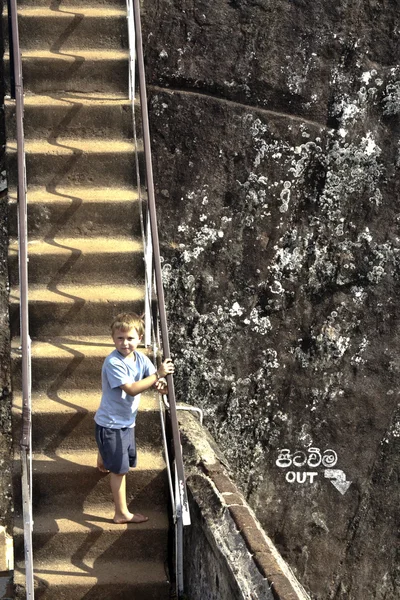 Boy climbs up the rocky stairs to the old fortress of Sigiria in — Stock Photo, Image