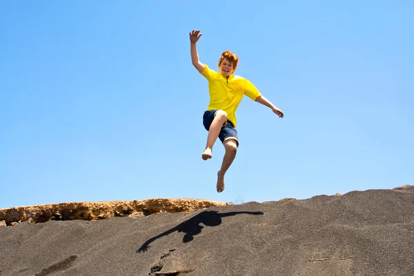 男孩有好玩的跳跃中的 beachin 海洋沙丘 — 图库照片