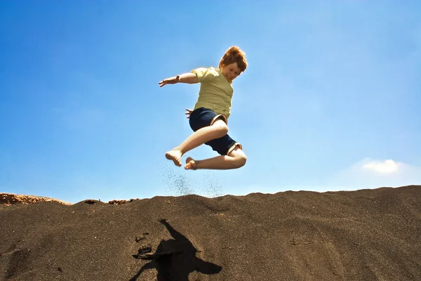 Chłopiec ma zabawy skoki po wydmach beachin oceanu — Zdjęcie stockowe