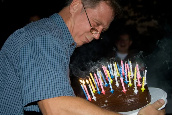 Hombre sopla sus velas de cumpleaños en el cumpleaños — Foto de Stock