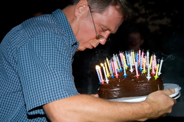 Homem apaga suas velas de aniversário no aniversário — Fotografia de Stock