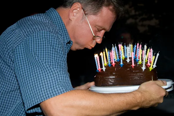 Man blows out his birthday candles at the birthday — Stock Photo, Image