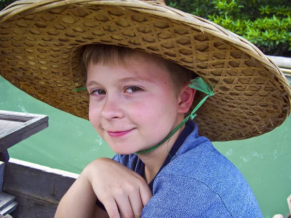 Menino usando um chapéu de palmeiras para proteção solar — Fotografia de Stock