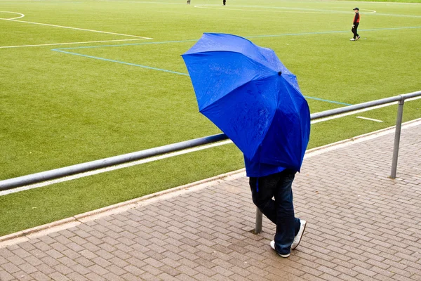 Man under umbrella is watching the football game — Stock Photo, Image
