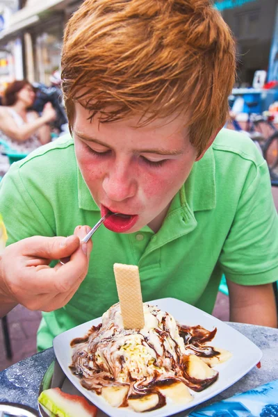 Criança comendo gelado em uma mesa ao ar livre — Fotografia de Stock