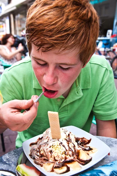 Kind eten icecream aan een buiten tafel — Stockfoto