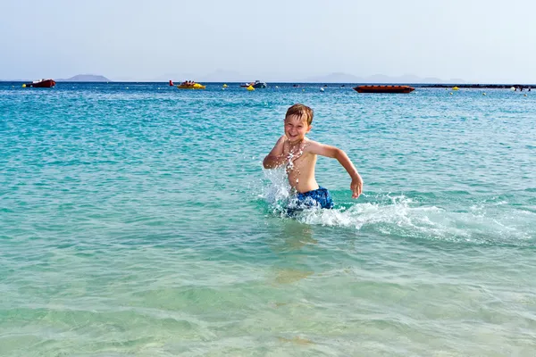 Αγόρι έχει διασκέδαση τρέχει στο νερό του ωκεανού — Φωτογραφία Αρχείου