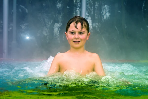 Мальчик получает удовольствие в открытом термальный бассейн в зимнее время — стоковое фото