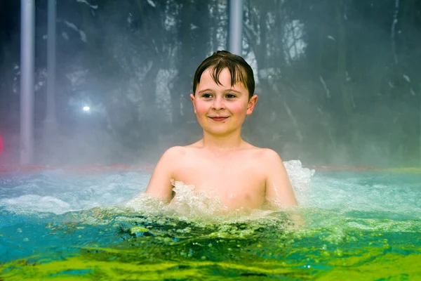 Chłopiec ma zabawy w odkryty basen termalny w okresie zimowym — Zdjęcie stockowe