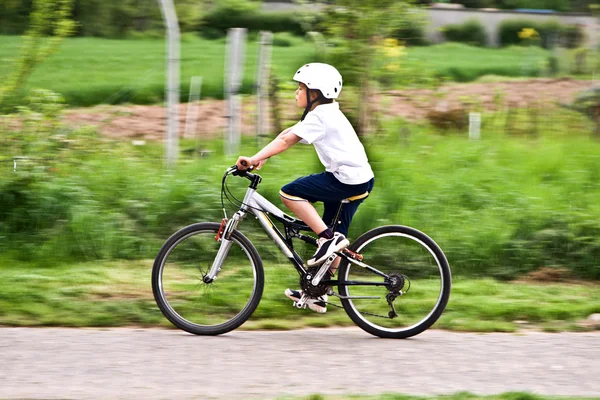 Jeune garçon avec casque fait du vélo de montagne — Photo