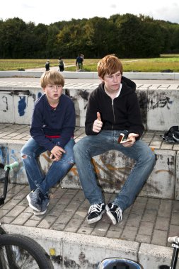 Cool boys sitting on a stone clipart