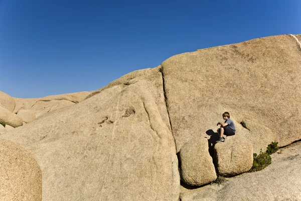 Chłopiec siedzi na skale — Zdjęcie stockowe