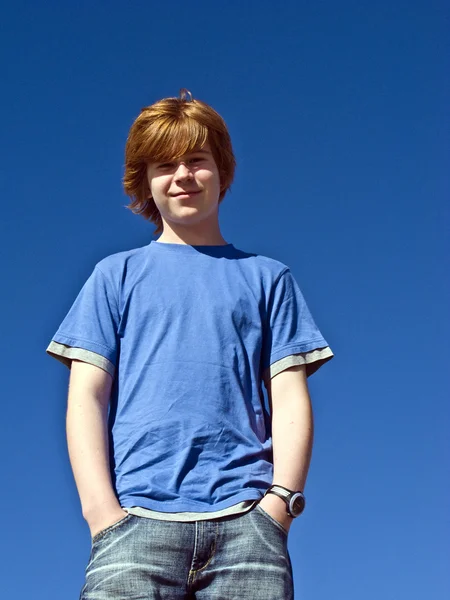 Мальчик улыбается под голубым небом — стоковое фото